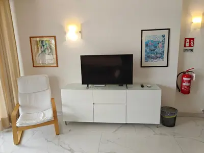 a living room with a tv and a white cabinet and a chair at Appartamento Aurelio - Vaticano in Rome