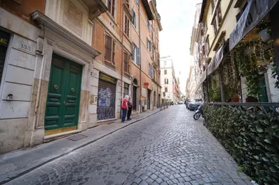 a person walking down a cobblestone street next to buildings at Elisa's Trevi Fountain BuddyRent in Rome