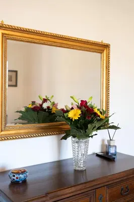 a vase of flowers on a table in front of a mirror at AURELIA LORIS HOUSE in Rome