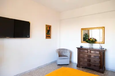 a bedroom with a tv and a chair and a dresser at AURELIA LORIS HOUSE in Rome