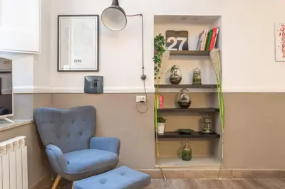 a living room with a blue chair and a book shelf at Central Charm near Piazza Navona - Cozy Loft for 2 in Rome