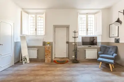 a living room with a blue chair and a television at Central Charm near Piazza Navona - Cozy Loft for 2 in Rome
