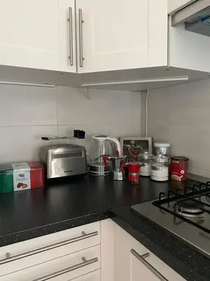 a kitchen with white cabinets and a black counter top at CASA BALU' in Rome
