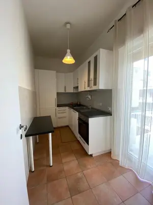 a kitchen with white cabinets and a table and a window at CASA BALU' in Rome