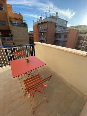 a red table and a chair on a balcony at CASA BALU' in Rome