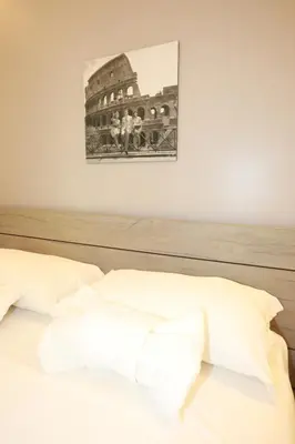 a bed with white sheets and a picture on the wall at Unique Luxury Stay in Rome