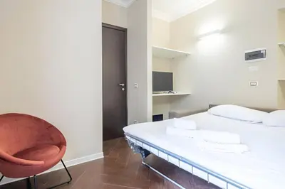 a bedroom with a white bed and a chair at Ghetto BuddyRent in Rome