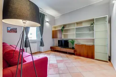 a living room with a red couch and a television at Historia et Elegantia - vicino il Colosseo, Circo Massimo e Trastevere in Rome