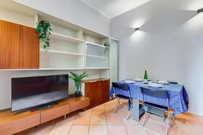 a dining room with a blue table and a large tv at Historia et Elegantia - vicino il Colosseo, Circo Massimo e Trastevere in Rome