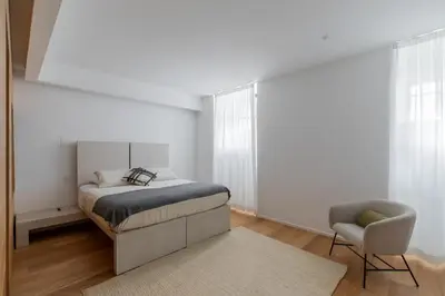 a white bedroom with a bed and a chair at Saint Peter Caesar Suites in Rome