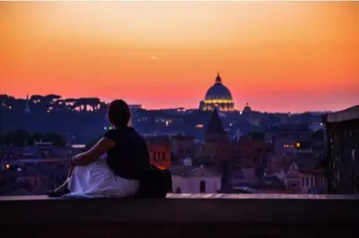 a woman sitting on a ledge watching the sunset at Interno 4 in Rome - Aventino e Circo Massimo in Rome