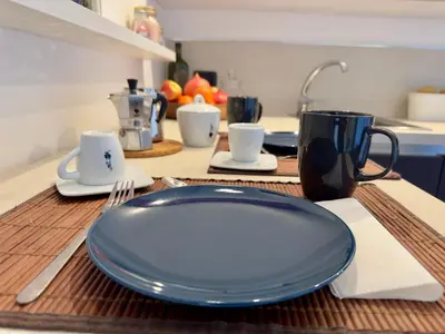 a kitchen with a table with two plates and wine glasses at Interno 4 in Rome - Aventino e Circo Massimo in Rome