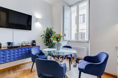 a living room with a glass table and blue chairs at Clemente XII Al Quirinale House in Rome