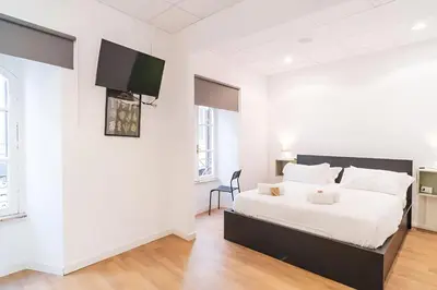 a white bedroom with a bed and a flat screen tv at Trevi's BuddyRent in Rome