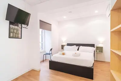 a white bedroom with a bed and a tv at Trevi's BuddyRent in Rome