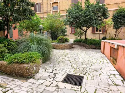 a garden with a stone walkway in front of a building at Domitia Vatican Luxury Apartment in Rome