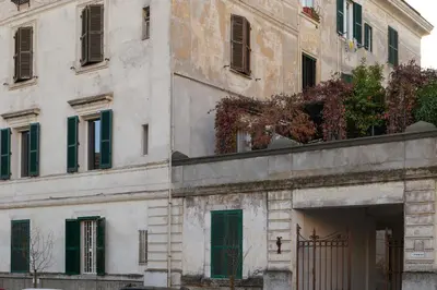 a building with green shuttered windows and a gate at Casa MastroiannI con Terrazzo in Rome