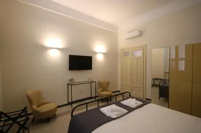 a bedroom with a bed and two chairs and a television at Irene's Home The Retreat in Rome