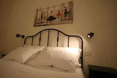 a bed with white pillows and a painting on the wall at Irene's Home The Retreat in Rome
