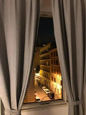 a view of a city street from a window with curtains at White King Rooms in Rome