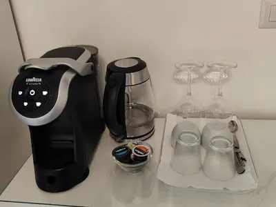 a counter with a coffee maker and wine glasses at White King Rooms in Rome