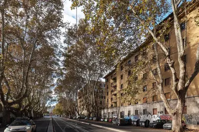 a street with cars parked on the side of a building at GuestHost - Roma Trastevere Vibes Apartment in Rome