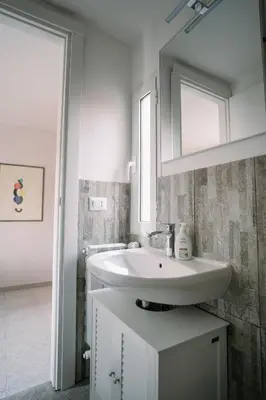a white bathroom with a sink and a mirror at Romantic apartment [Metro A Ponte Lungo] in Rome