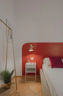 a bedroom with a red wall and a bed with a table at Boho Chic Apartment By Nosdom Properties in Rome