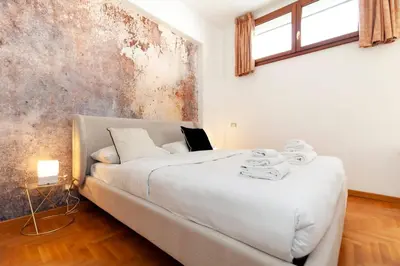 a white bed in a room with a rusty wall at CAVALLEGGERI HOUSE in Rome