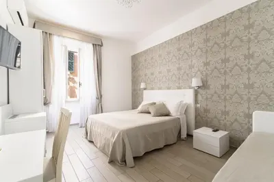 a white bedroom with a bed and a wall at Le Suite dei Mercanti in Rome