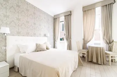 a white bedroom with a white bed and a table at Le Suite dei Mercanti in Rome