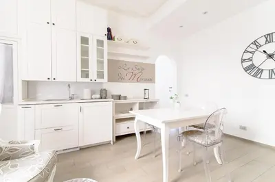 a white kitchen with a white table and a clock at Le Suite dei Mercanti in Rome
