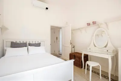 a white bedroom with a white bed and a mirror at Vittoria in Trastevere Apartment in Rome