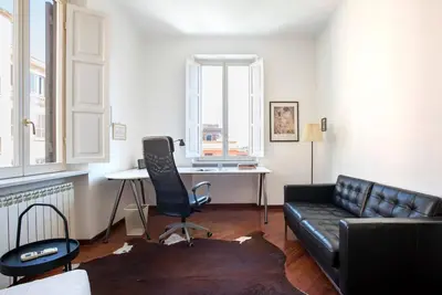 a living room with a black leather couch and a desk at Vittoria in Trastevere Apartment in Rome