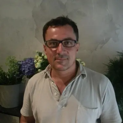 a man wearing glasses sitting next to a vase of flowers at Vaticana Ottaviani Roma in Rome
