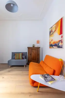 a living room with an orange couch and a table at Urban Chic 2 BR Vatican Escape in Rome