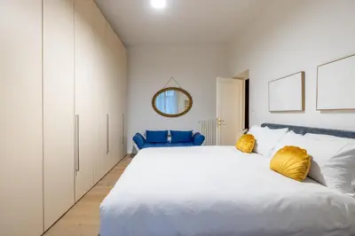 a bedroom with a large white bed with yellow pillows at Urban Chic 2 BR Vatican Escape in Rome