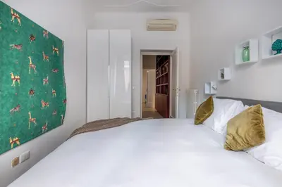 a bedroom with a large white bed with gold pillows at Urban Chic 2 BR Vatican Escape in Rome