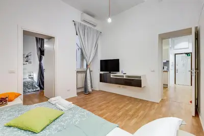 a white bedroom with a bed and a flat screen tv at TRASTEVERE SUITE EXPERIENCE in Rome