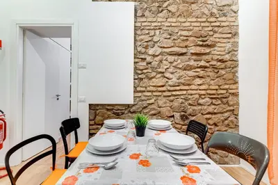 a dining room with a table with chairs and a stone wall at TRASTEVERE SUITE EXPERIENCE in Rome