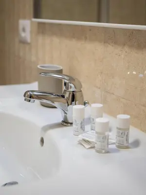 a bathroom sink with a faucet and some moisturizers at Minerva House Pantheon in Rome