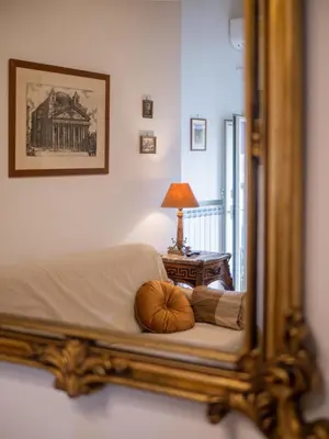 a mirror reflecting a bedroom with a bed and a lamp at Minerva House Pantheon in Rome