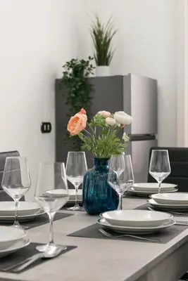 a table with glasses and a vase with flowers on it at Appartamento via di Porta Labicana in Rome