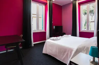 a room with a bed and a table and windows at SABA SUITE ROMA in Rome