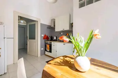 a kitchen with a table and a vase with flowers on it at Romeo. Luminoso appartamento al centro di Roma in Rome