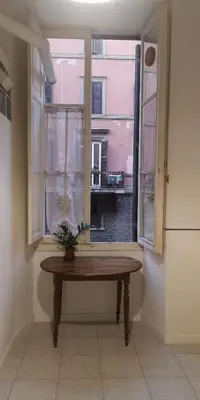 a table in front of a window with a plant on it at Romeo. Luminoso appartamento al centro di Roma in Rome