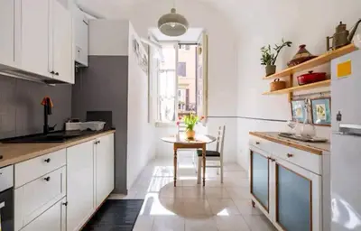 a kitchen with white cabinets and a small table at Romeo. Luminoso appartamento al centro di Roma in Rome