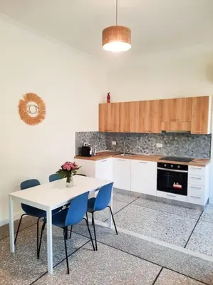 a kitchen with a white table and blue chairs at RomAntica Lemon Apartment in San Giovanni in Rome