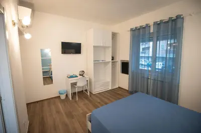 a bedroom with a bed and a desk and a window at ROMECOMING Ostiense Guest House in Rome