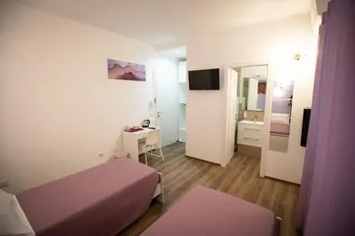 a small room with a bed and a desk at ROMECOMING Ostiense Guest House in Rome